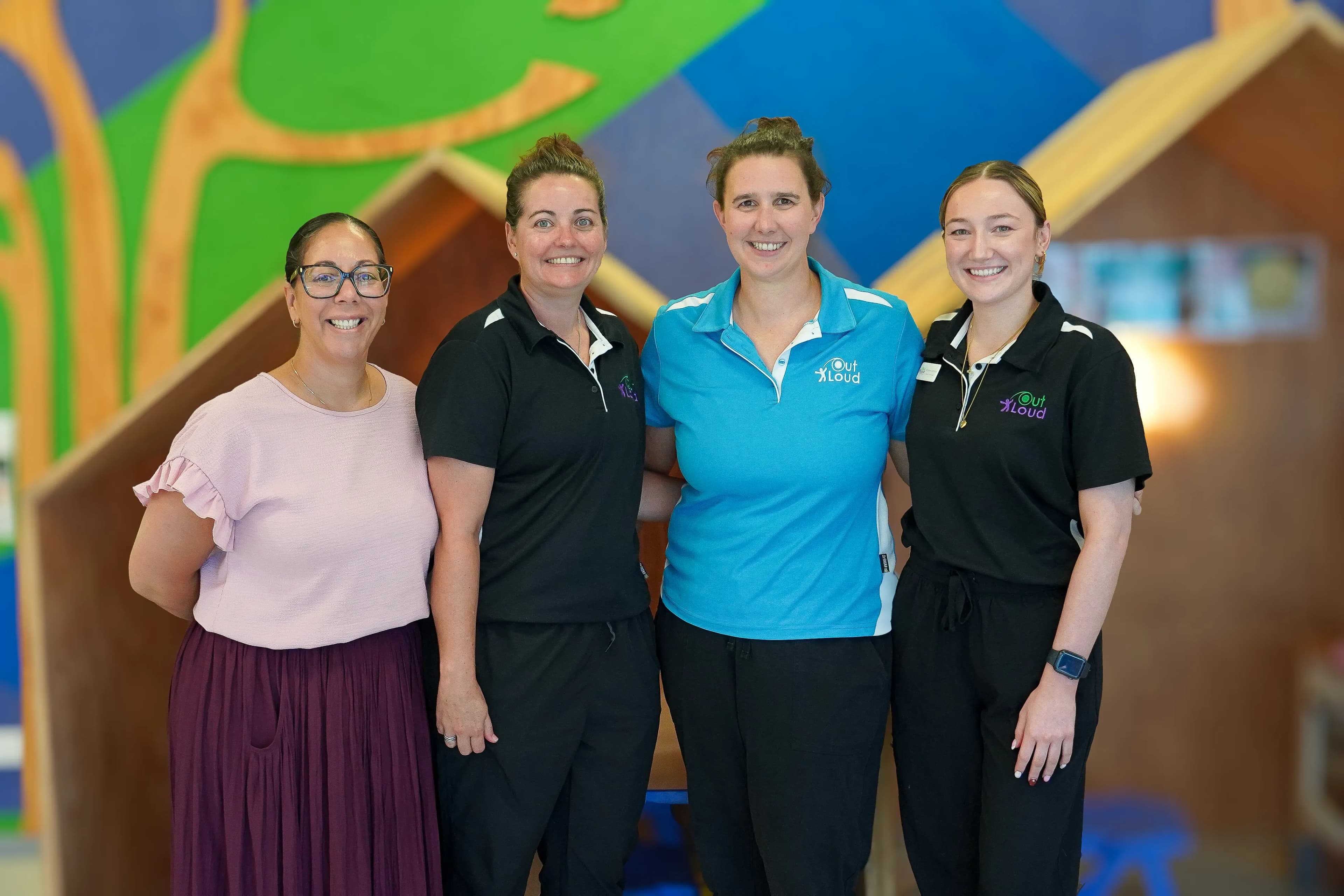 Four people standing infront of a colourful wall 